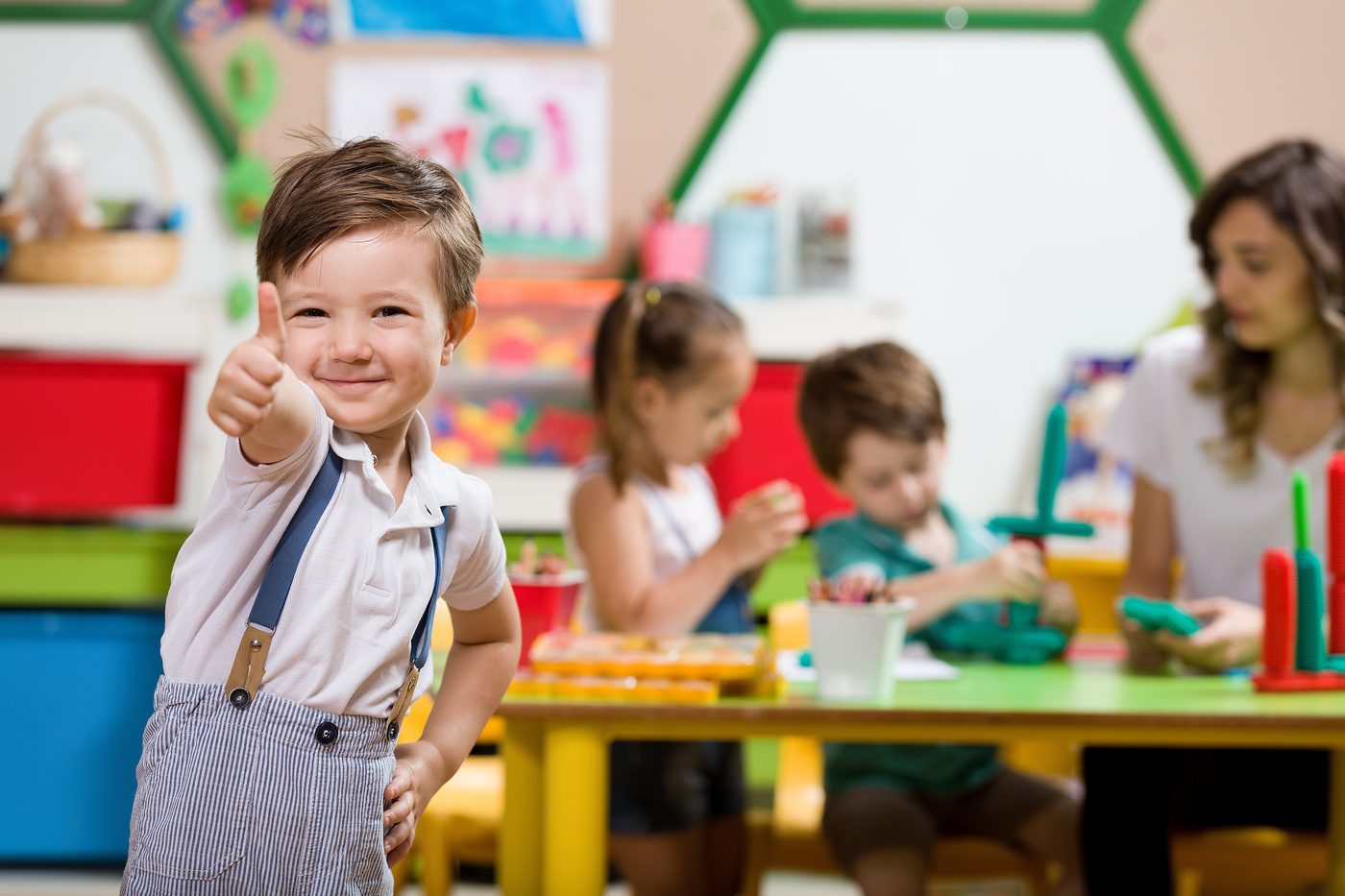 Preschooler giving a thumbs up in a bright classroom — DLS Innovations preschool photography